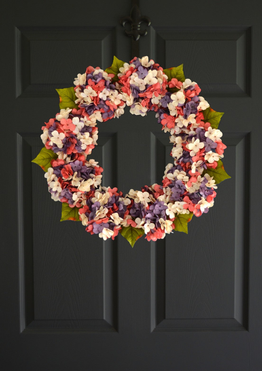 Coral and lavender hydrangea wreath displayed on front door for spring farmhouse decor
