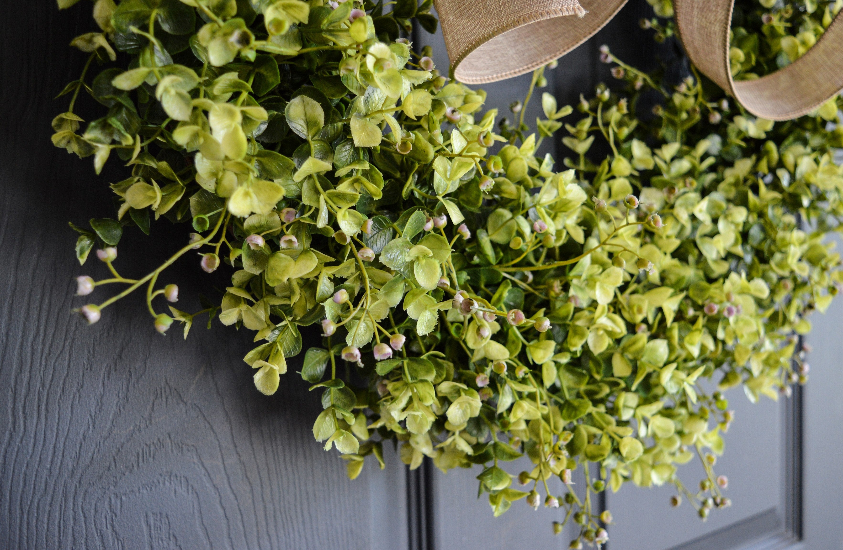 Close up of realistic faux eucalyptus and boxwood greenery on handmade grapevine wreath