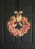 Handmade pink hydrangea wreath displayed on front door entryway