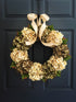Green hydrangea front door wreath hanging on farmhouse style entryway