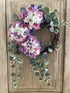 Floral wreath with pink, purple, and white flowers on a wooden door